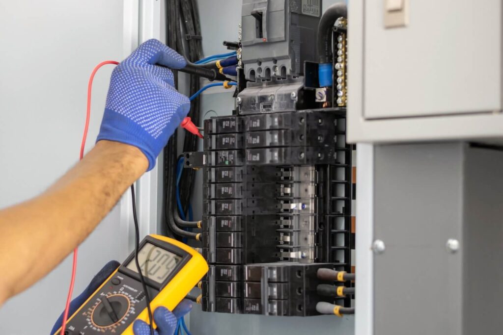 Electrician using digital meter to measure voltage at the circuit breaker control cabinet